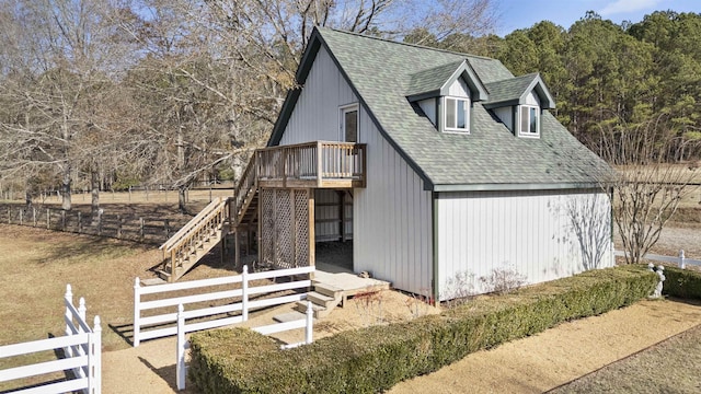 view of property exterior featuring roof with shingles, fence, stairway, and a wooden deck