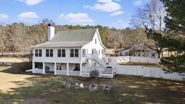 rear view of property with a yard, a chimney, a fenced backyard, and a wooden deck