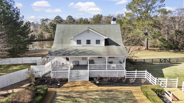 farmhouse-style home featuring a front lawn, a chimney, a fenced backyard, and a wooden deck