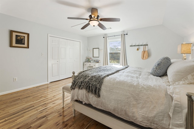 bedroom featuring a closet, vaulted ceiling, ceiling fan, wood finished floors, and baseboards