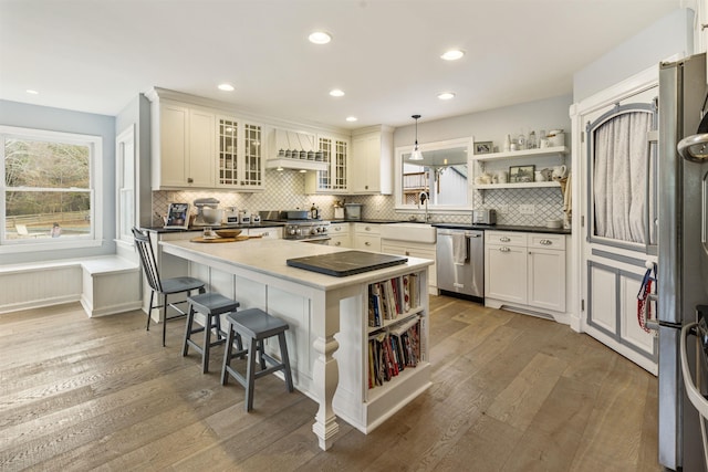 kitchen with hardwood / wood-style flooring, appliances with stainless steel finishes, open shelves, and backsplash