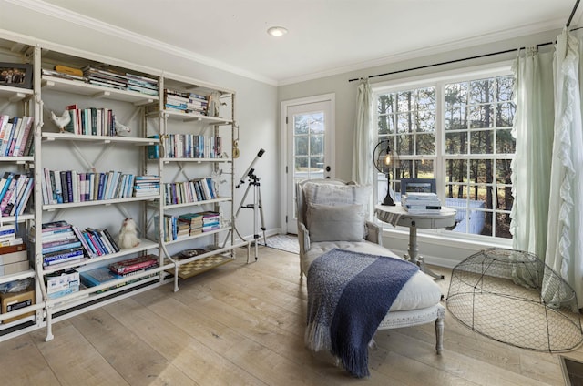 living area featuring crown molding, baseboards, and hardwood / wood-style floors