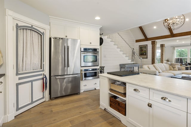 kitchen featuring white cabinets, ornate columns, light wood-style flooring, and stainless steel appliances