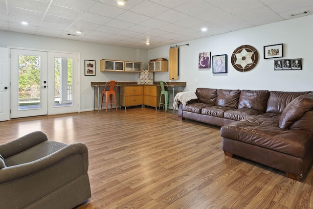 living room with a paneled ceiling, light wood-style floors, and visible vents