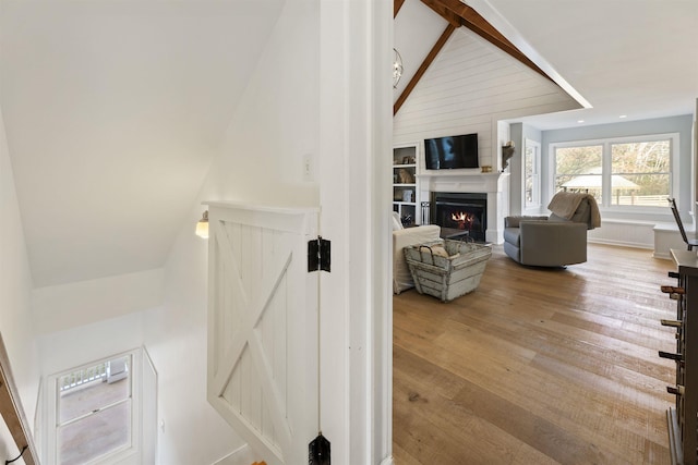 interior space featuring vaulted ceiling, a lit fireplace, and wood finished floors