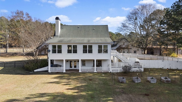 back of house with a fenced backyard, stairway, a lawn, and french doors