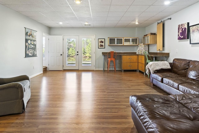 living area with a paneled ceiling, baseboards, dark wood-style flooring, and french doors