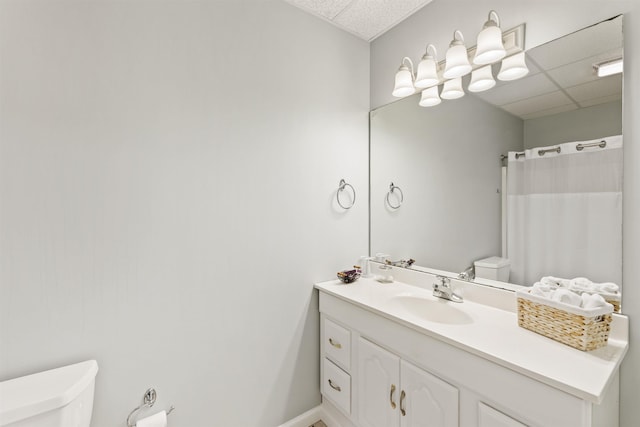 bathroom featuring a paneled ceiling, toilet, a shower with shower curtain, vanity, and baseboards