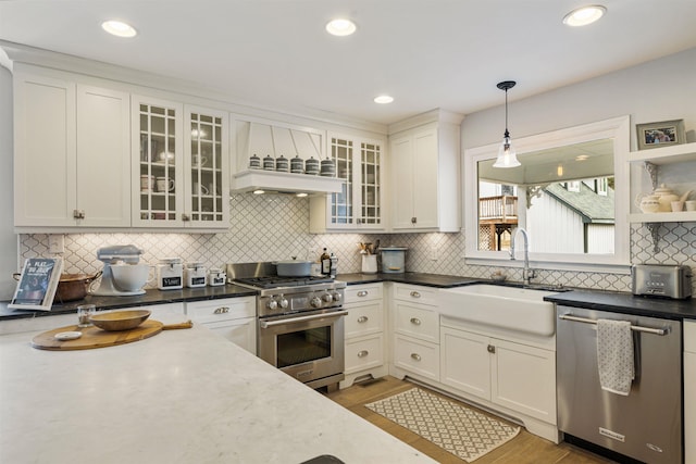 kitchen featuring stainless steel appliances, pendant lighting, white cabinets, and a sink