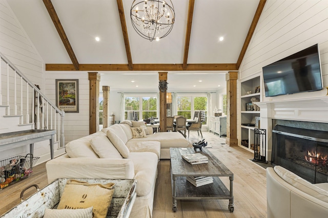 living area with wooden walls, a fireplace with flush hearth, stairway, beamed ceiling, and light wood-style floors