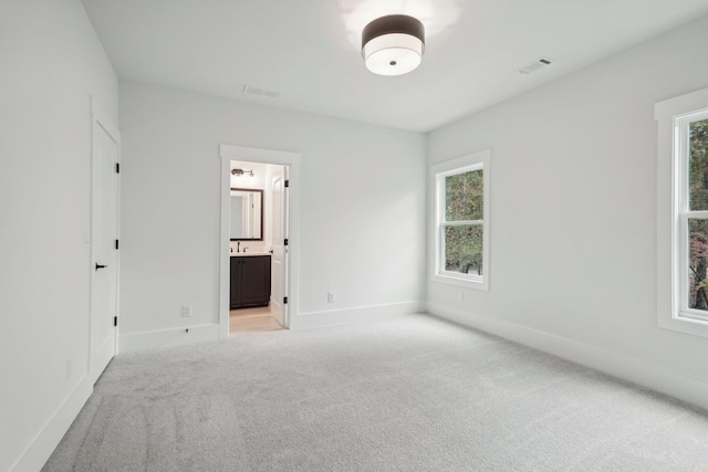 unfurnished bedroom with light carpet, visible vents, ensuite bathroom, and baseboards