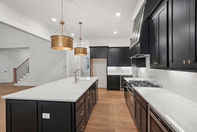 kitchen with light stone countertops, light wood-style flooring, a sink, stainless steel range, and tasteful backsplash