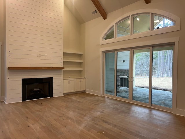 unfurnished living room with beam ceiling, wood finished floors, a fireplace, and visible vents