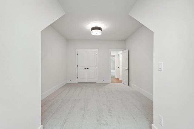 interior space featuring light carpet, a closet, and baseboards