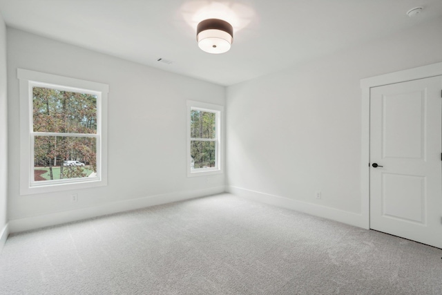 carpeted spare room with visible vents and baseboards