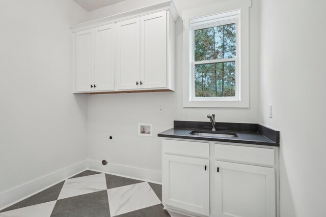 laundry area featuring electric dryer hookup, washer hookup, a sink, cabinet space, and baseboards