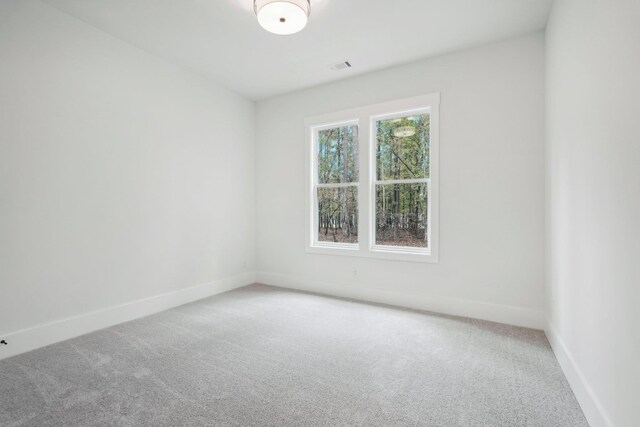 unfurnished room with visible vents, baseboards, and light colored carpet