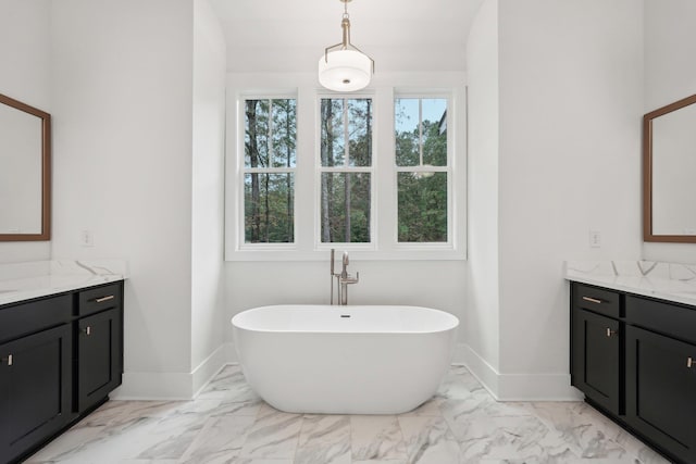 bathroom featuring marble finish floor, vanity, baseboards, and a freestanding tub