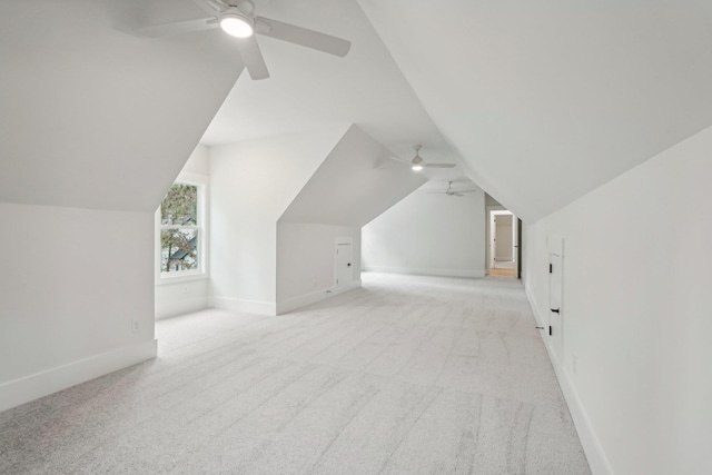 additional living space with light colored carpet, ceiling fan, baseboards, and vaulted ceiling