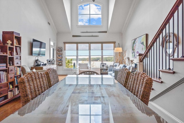 living room with crown molding, light hardwood / wood-style floors, and a high ceiling