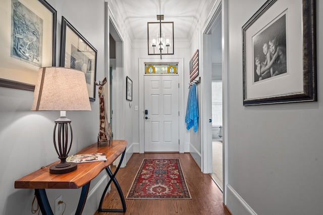 foyer with an inviting chandelier, ornamental molding, and dark hardwood / wood-style flooring