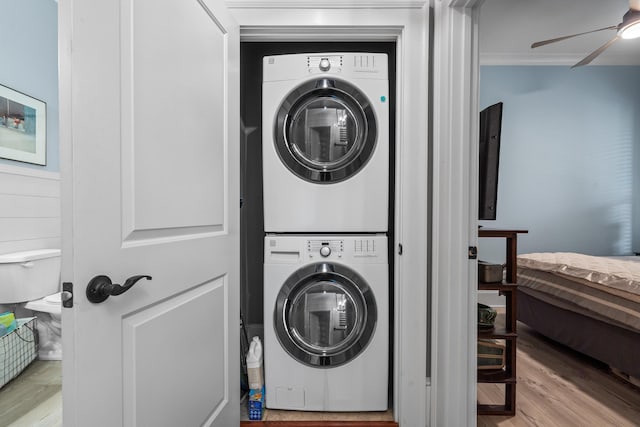 laundry area featuring ceiling fan, stacked washer / drying machine, and light hardwood / wood-style floors