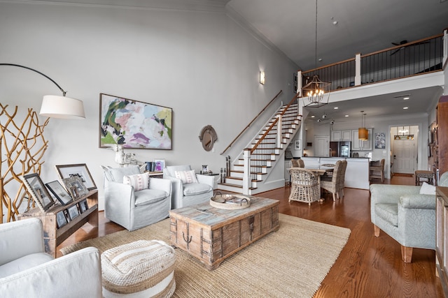 living room featuring dark wood-type flooring, ornamental molding, a chandelier, and a high ceiling