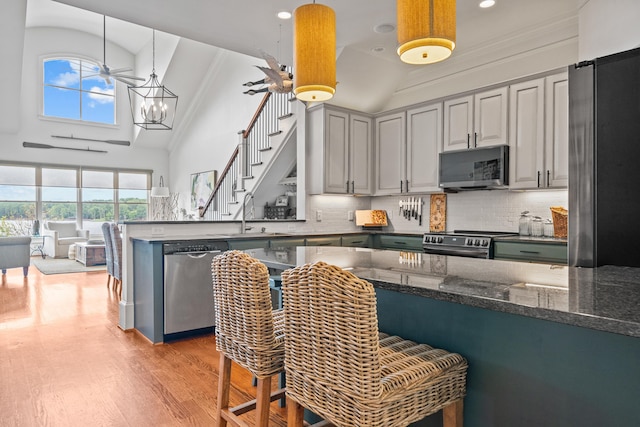 kitchen featuring sink, a breakfast bar area, dark stone counters, pendant lighting, and stainless steel appliances