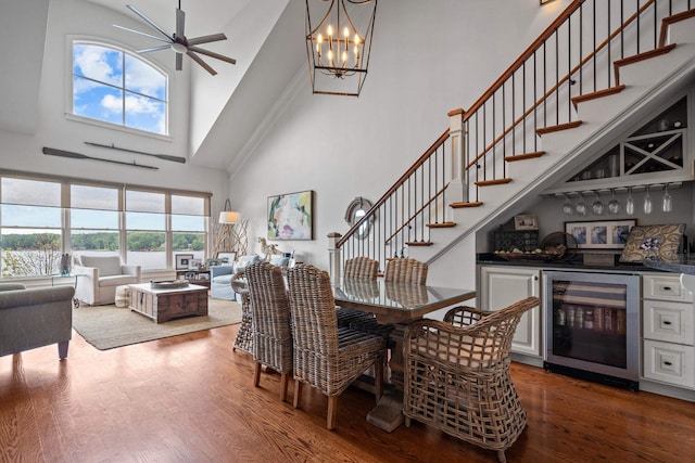 dining space with wood-type flooring, beverage cooler, a high ceiling, and bar area