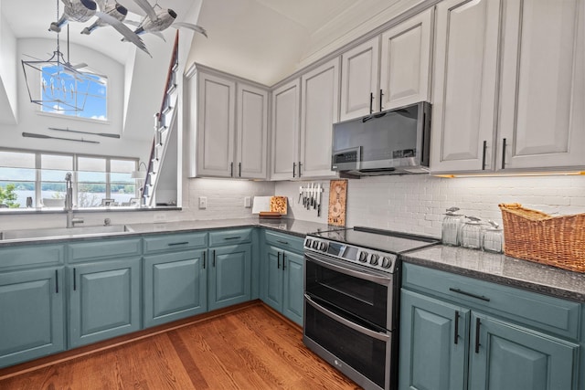 kitchen featuring appliances with stainless steel finishes, tasteful backsplash, sink, light hardwood / wood-style floors, and blue cabinetry