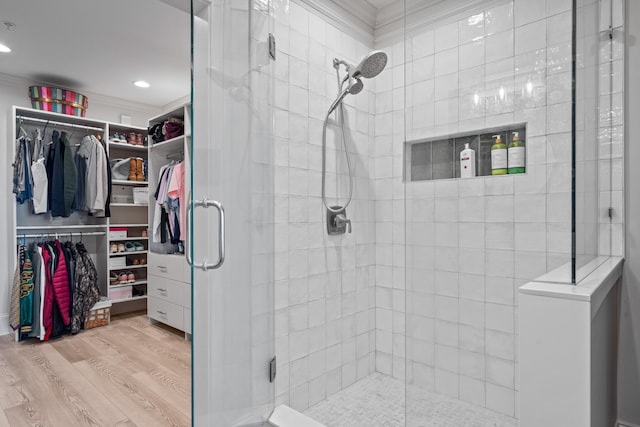 bathroom with ornamental molding, wood-type flooring, and a shower with door