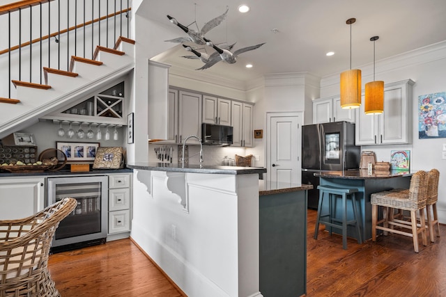 kitchen with wine cooler, a breakfast bar, stainless steel refrigerator, dark hardwood / wood-style flooring, and kitchen peninsula