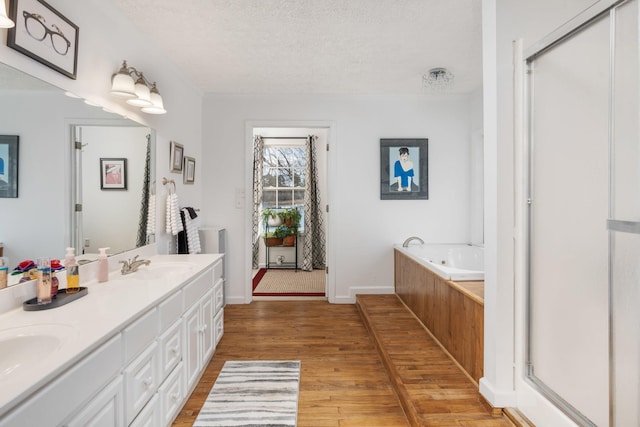 bathroom featuring vanity, hardwood / wood-style floors, plus walk in shower, and a textured ceiling