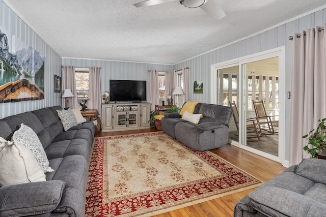 living room featuring crown molding, ceiling fan, a textured ceiling, and light hardwood / wood-style floors