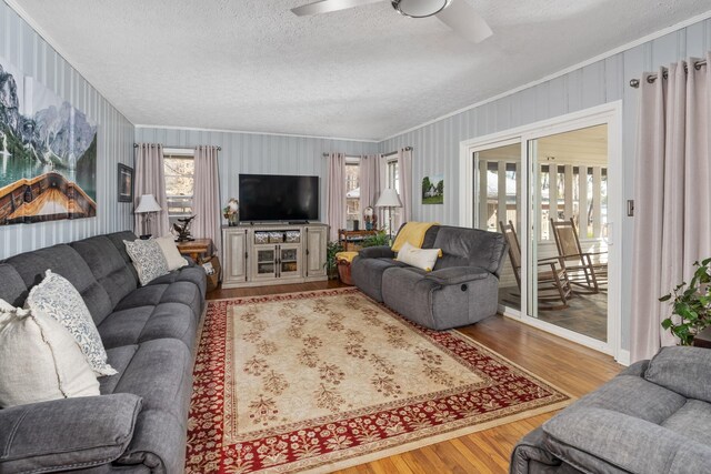 living room featuring crown molding, ceiling fan, a textured ceiling, and light hardwood / wood-style floors