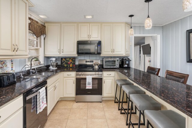 kitchen with hanging light fixtures, electric range, sink, and a kitchen bar