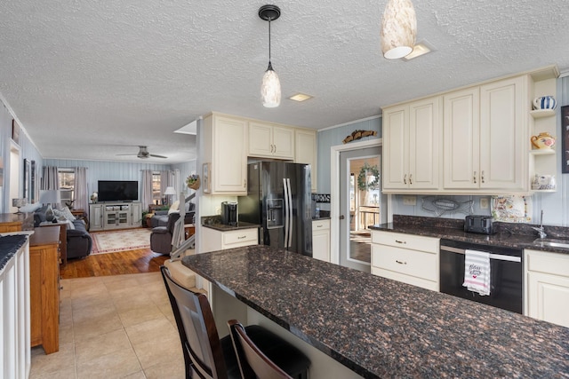 kitchen with light tile patterned floors, ceiling fan, black appliances, decorative light fixtures, and dark stone counters