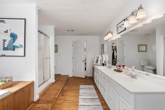 bathroom with vanity, hardwood / wood-style floors, a shower with door, and toilet