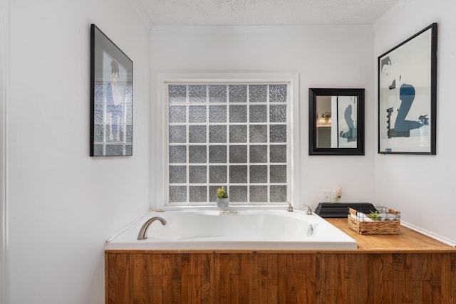 bathroom featuring ornamental molding, a bath, and a textured ceiling