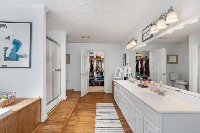 bathroom with walk in shower, toilet, wood-type flooring, a textured ceiling, and vanity