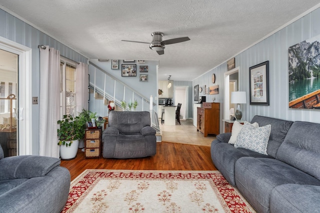 living room featuring crown molding, wood-type flooring, a textured ceiling, and ceiling fan