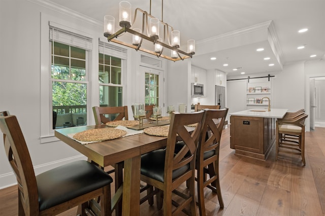 dining room with ornamental molding, a barn door, sink, and dark wood-type flooring