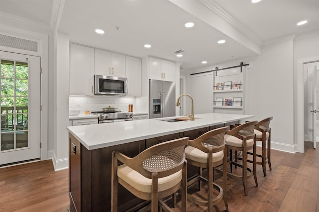 kitchen with high quality appliances, an island with sink, a barn door, and sink