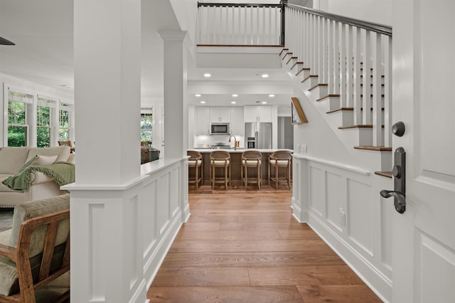 foyer entrance featuring sink, light hardwood / wood-style floors, and a towering ceiling