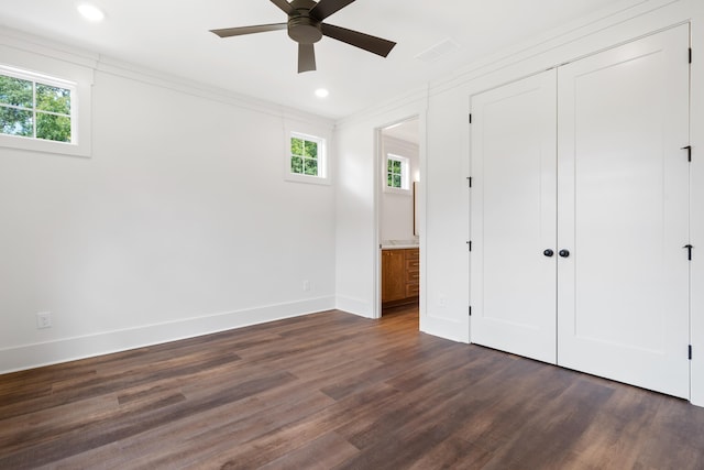 unfurnished bedroom with crown molding, a closet, dark hardwood / wood-style flooring, and multiple windows