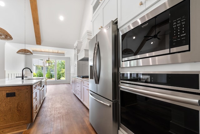 kitchen featuring sink, dark hardwood / wood-style floors, pendant lighting, stainless steel appliances, and white cabinets