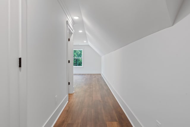 corridor with dark hardwood / wood-style floors and vaulted ceiling