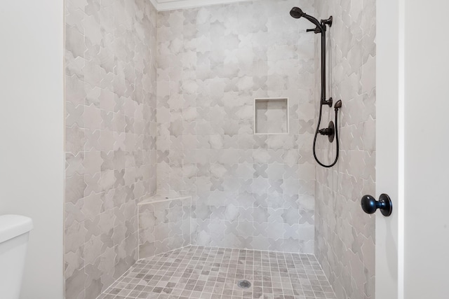 bathroom featuring tiled shower and toilet