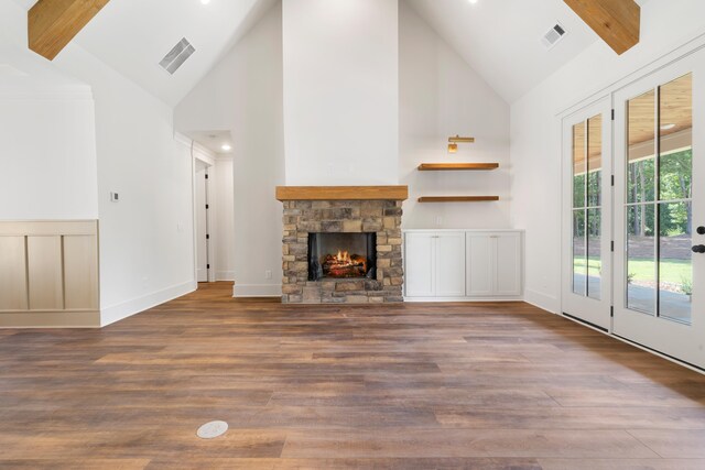 unfurnished living room with hardwood / wood-style flooring, a fireplace, high vaulted ceiling, and beamed ceiling