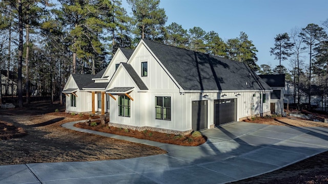 2050 Osprey Poynte, Greensboro, GA 30642 - view of front facade featuring board and batten siding, driveway, a standing seam roof, a garage, and a metal roof